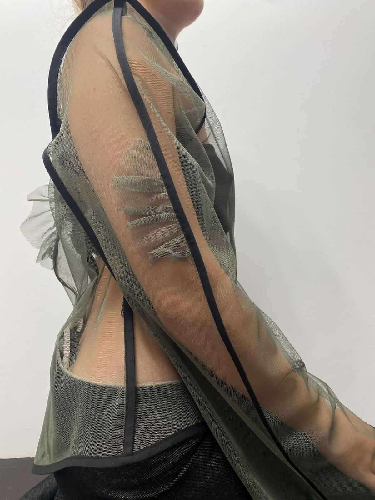 Close up to the right sleeve of a khaki green see-through top