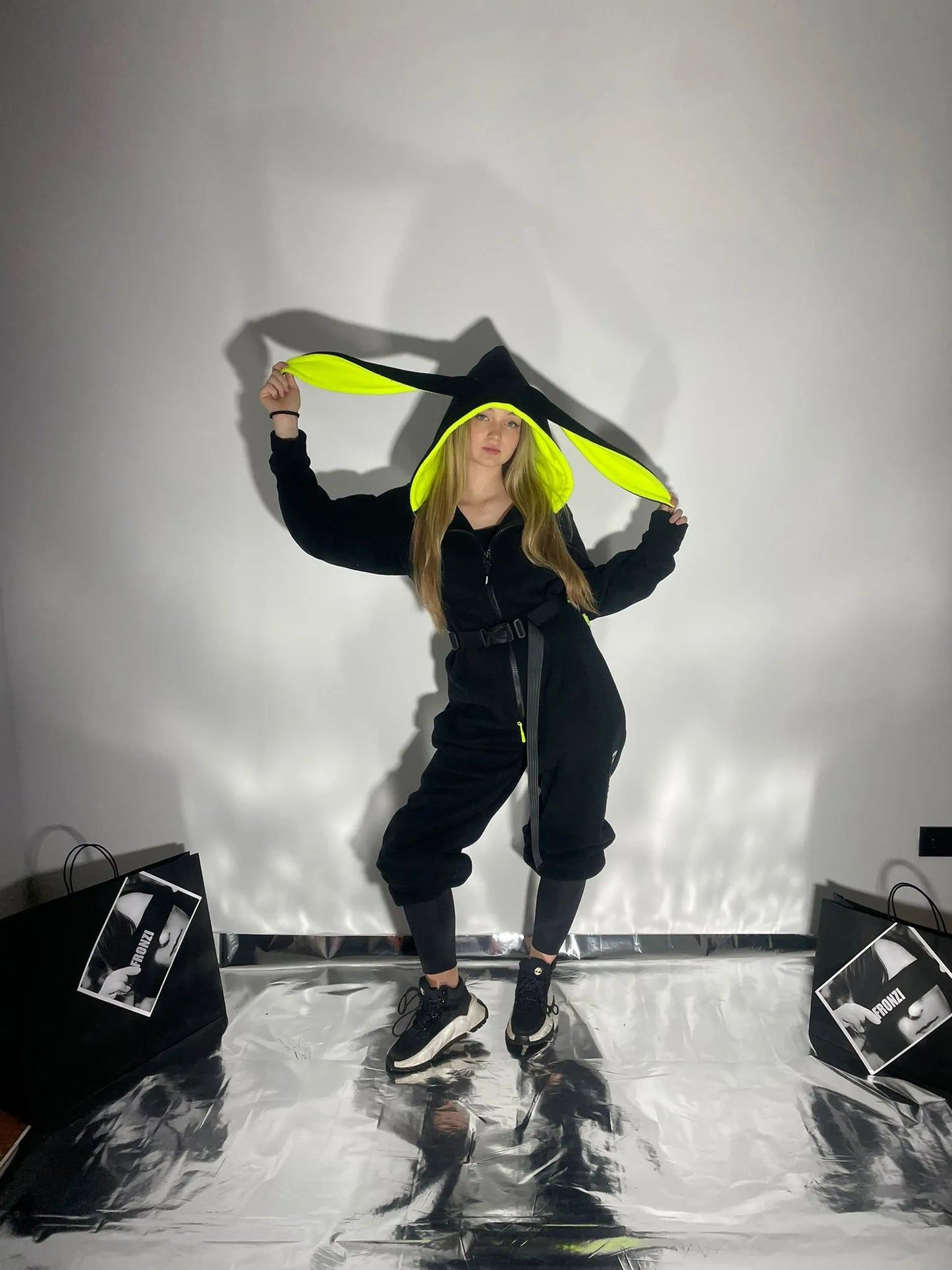 Model holding the ears on her black fleece onesie with neon details