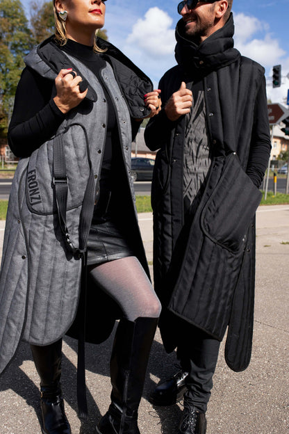 A man and woman both wearing long Fronzi vests, man is wearing a black vest and the woman is wearing a grey vest, they are in the sun, vests open