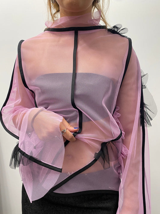 Person wearing a sheer pink dress with black trim on a white background