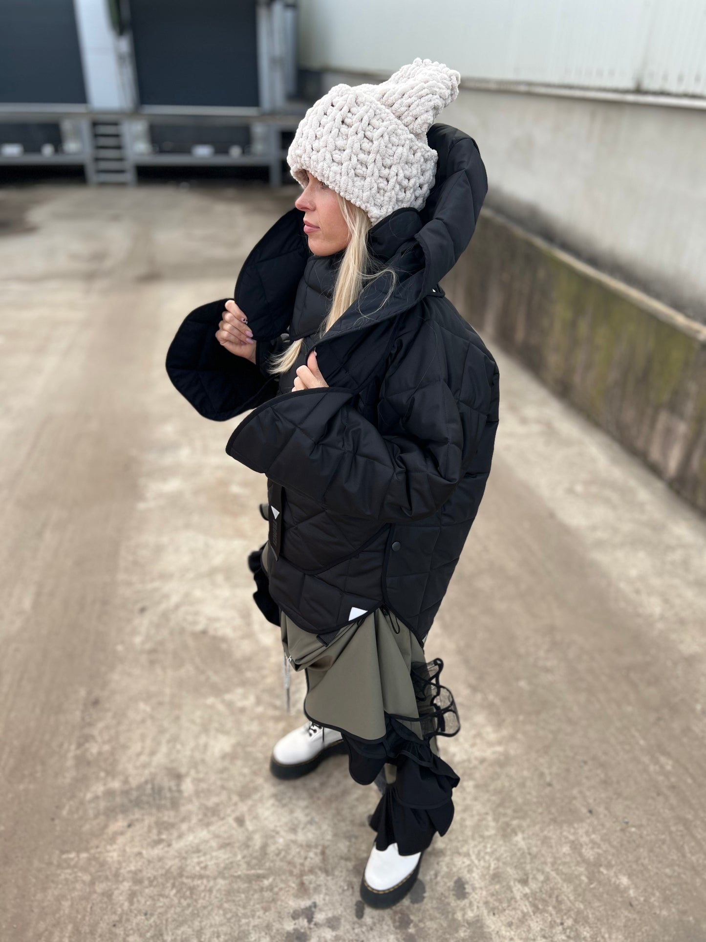 Blond model wearing short quilted hooded jacket in outdoor setting