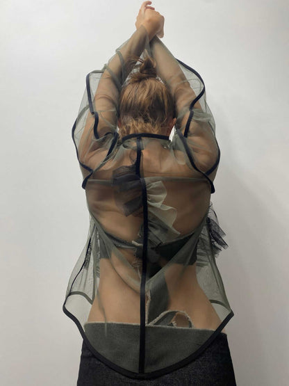 Model wearing khaki green see-through top with her arms help above her head