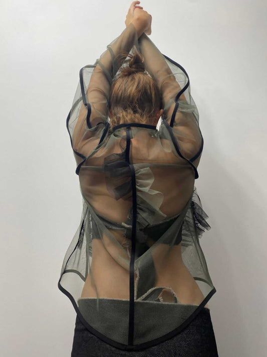 Model wearing khaki green see-through top with her arms help above her head