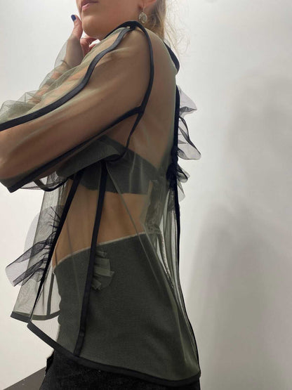 Model wearing a khaki green sheer top, view from the side