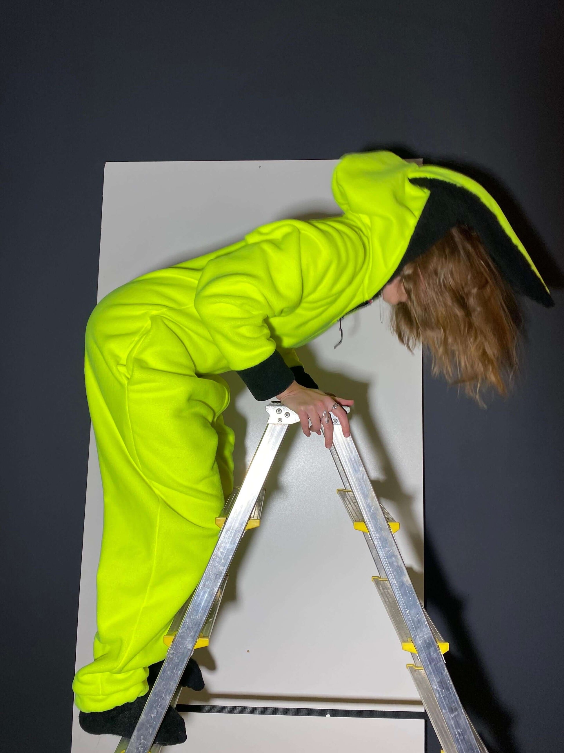 Model in movement wearing a neon yellow onesie, side profile