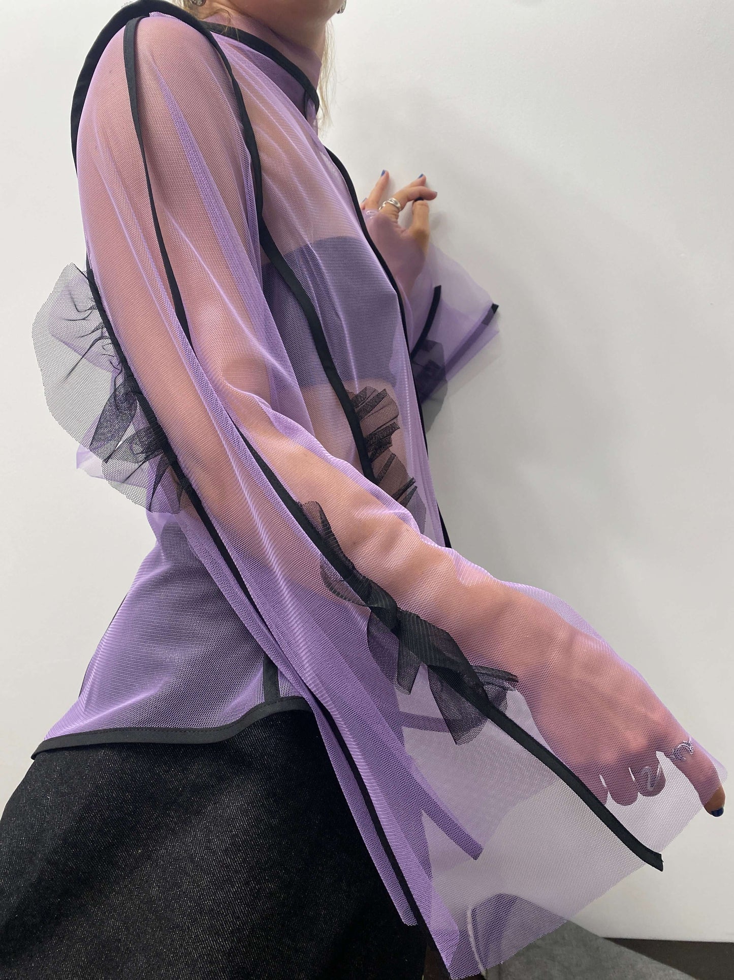 Side view of purple see-through top with black frills and lines along the sleeves