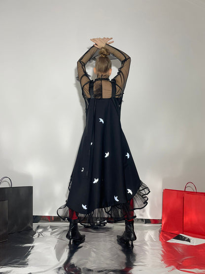 Model wearing a black dress with small reflective birds, view from the back