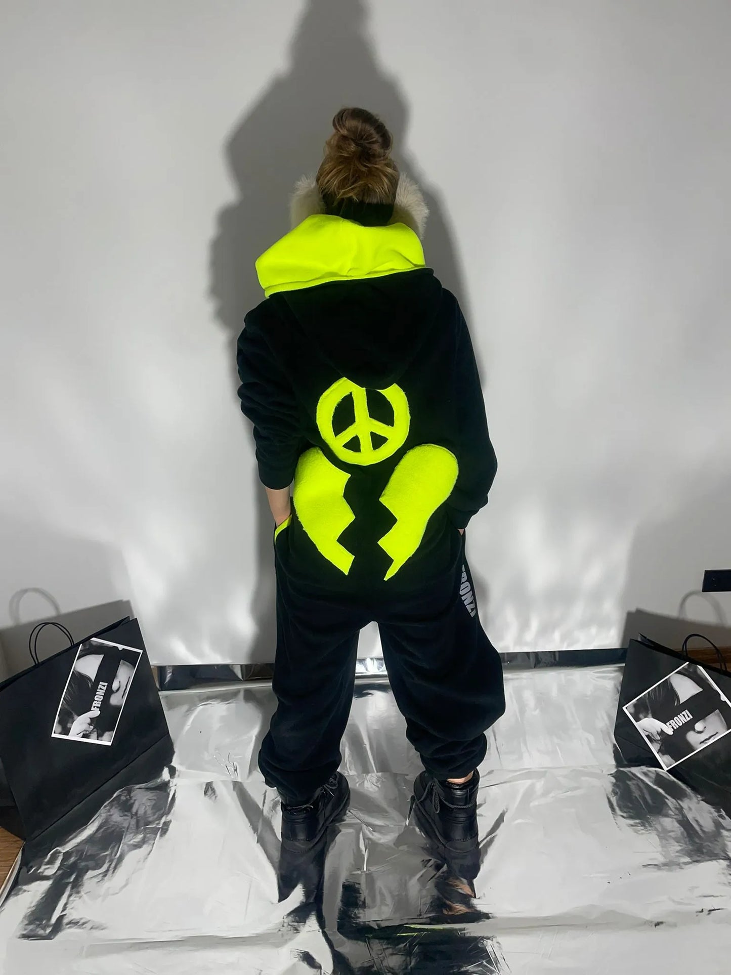 Black warm onesie with a broken neon hear and a peace sign shot from the back