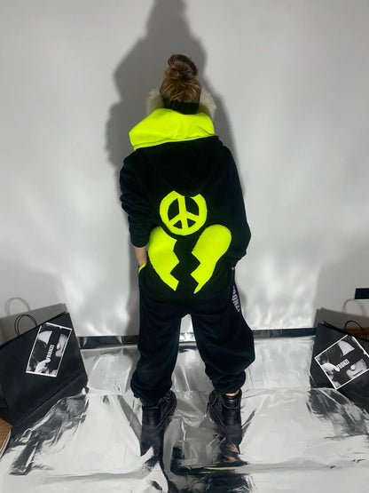 Black warm onesie with a broken neon hear and a peace sign shot from the back