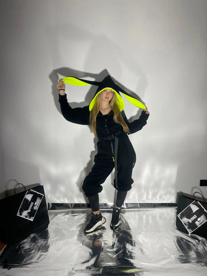Model holding the ears on her black fleece onesie with neon details
