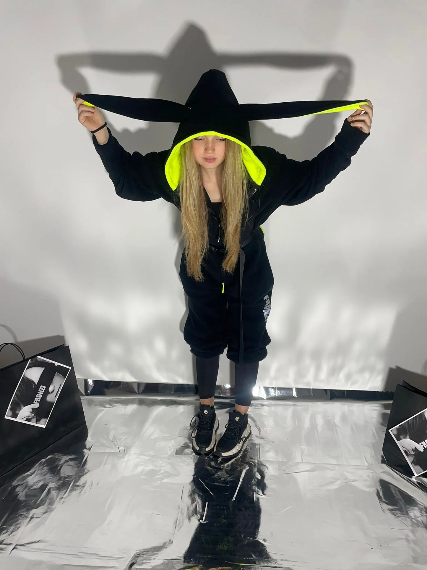 Model holding the ears on a black onesie, view from the front