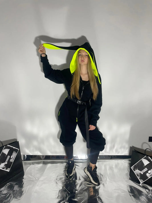 Model wearing a black fleece onesie with neon color details, view from the front