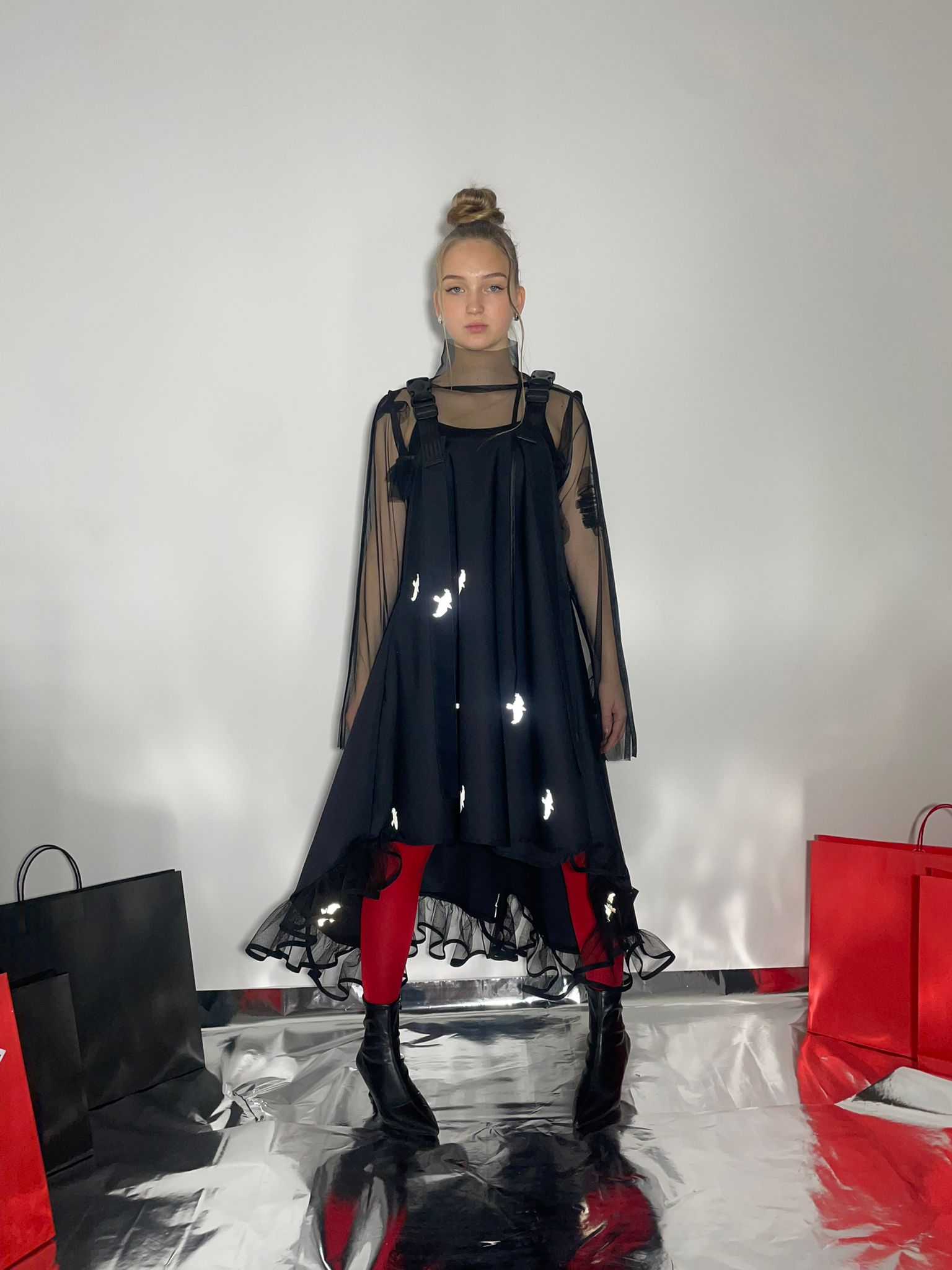 Video of model wearing a black dress with reflective birds with a Fronzi bag in her hands and then walking away form the shot