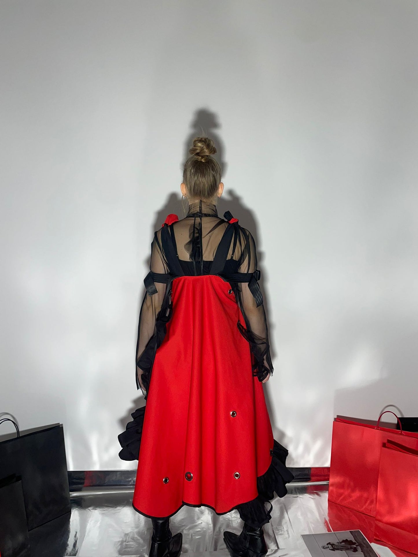 Model wearing a red dress with black frill details, view from the back